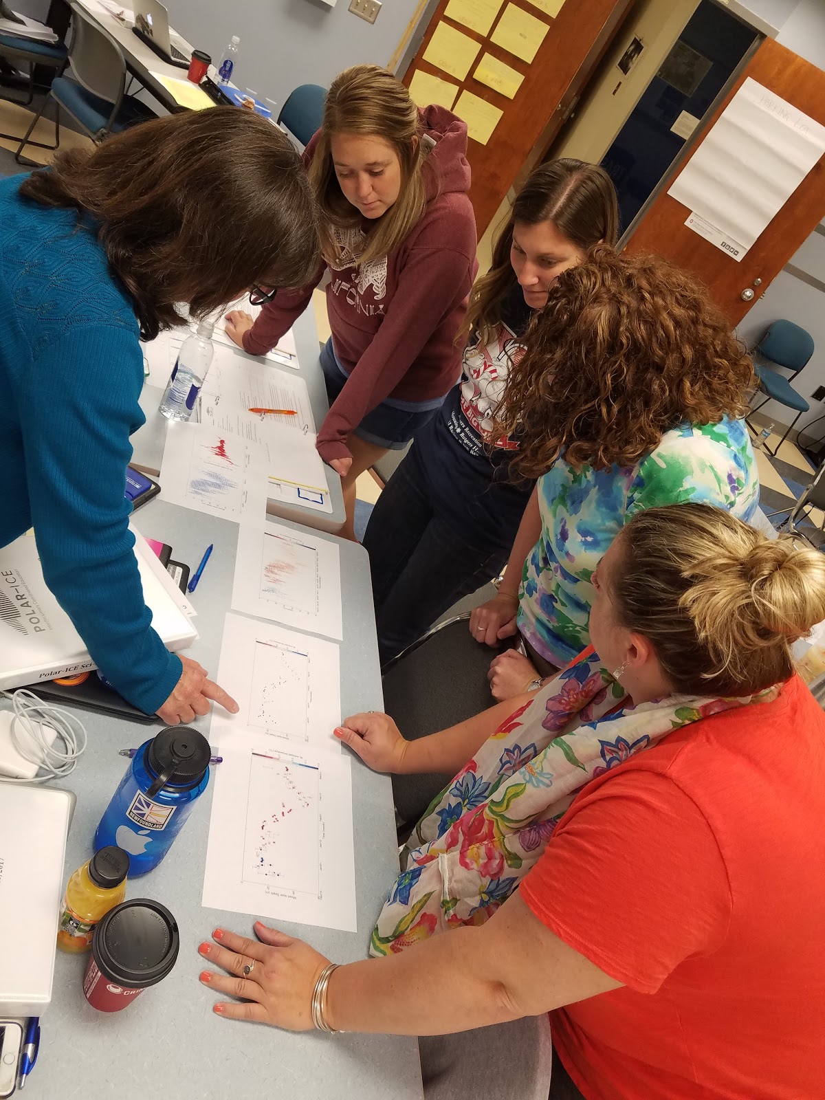 K-12 teachers stand around a table looking at some graphs